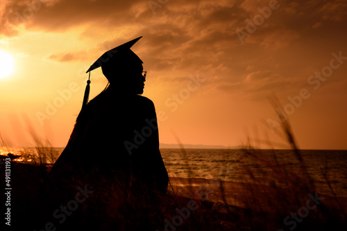 Silhouette of university graduated woman in sunset sky