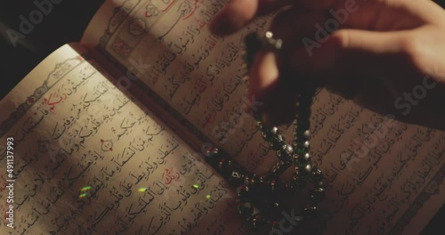 Shot of an opened Quran and s person doing dhikr on his prayer beads photo