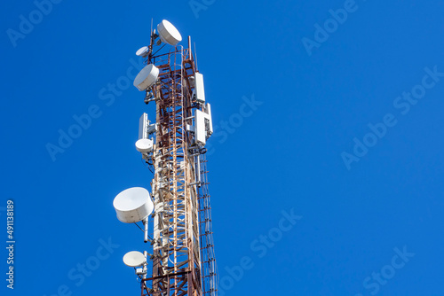 Telecommunications tower with cellular antenna on blue sky background. Look up. photo