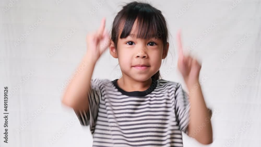 Cute little girl pointing her finger up to empty place and looking at the camera over a white studio background. Cute little girl pointing her finger up to empty place and looking at the camera over a white studio background.