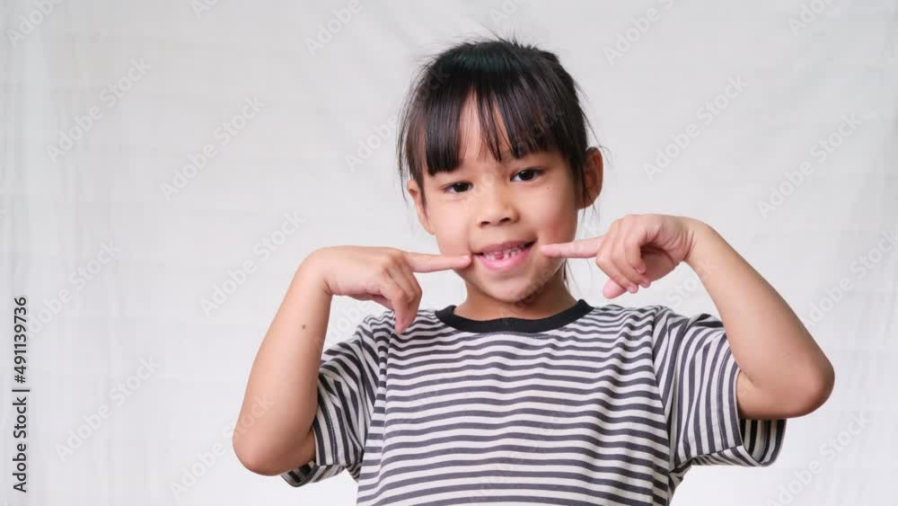 Cute Asian girl, 6 years old, smiling brightly showing broken baby teeth. Oral health and dental care in children Cute Asian girl, 6 years old, smiling brightly showing broken baby teeth. Oral health and dental care in children