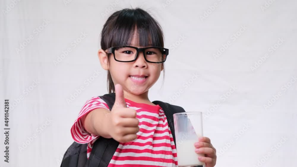 Cute schoolgirl drinking milk from a glass before going to school. Healthy nutrition for children. back to school concept Cute schoolgirl drinking milk from a glass before going to school. Healthy nutrition for children. back to school concept