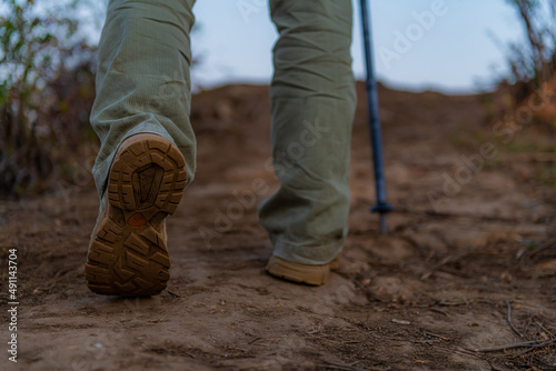 Feet of male climber walking on a hiking trail . Active man traveling on nature.
