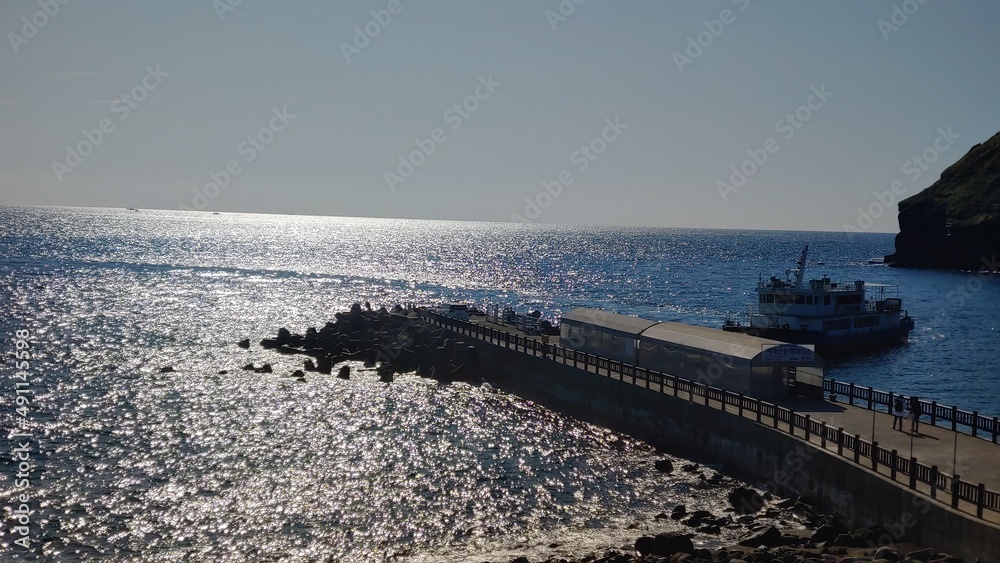 A dock with sparkling waves and a passenger ship.