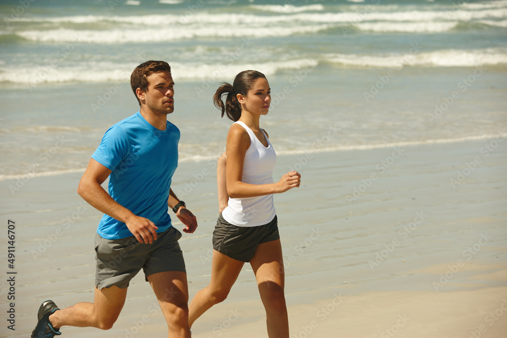 This couple takes being fit serious. Shot of a young couple jogging together on the beach. This couple takes being fit serious. Shot of a young couple jogging together on the beach.