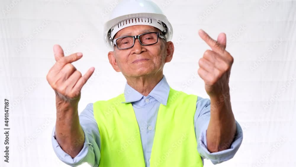 Happy senior engineering architect wearing a vest and helmet makes mini hearts with his hands on white background in studio. Happy senior engineering architect wearing a vest and helmet makes mini hearts with his hands on white background in studio.