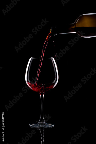 Still life with a glass of red wine and a bottle on a black background