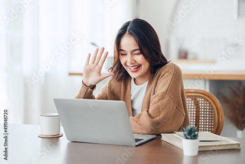 Fotografía Happy positive young asian woman enjoying online communication at home, Female u