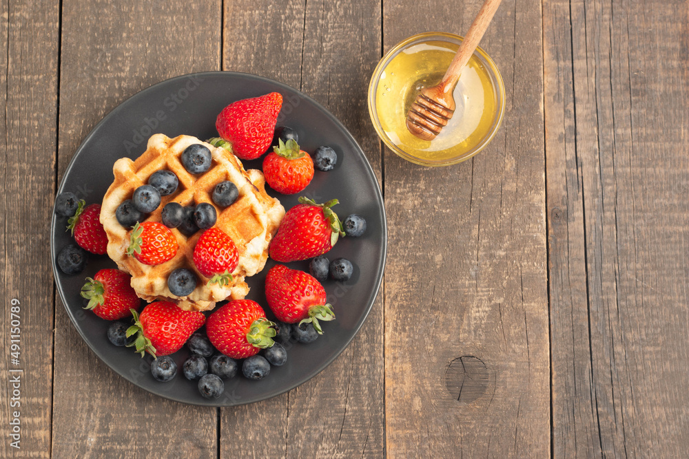 Fresh homemade food of berry Belgian waffles with honey, chocolate, strawberry, blueberry, maple syrup and cream. Healthy dessert breakfast concept with juice Fresh homemade food of berry Belgian waffles with honey, chocolate, strawberry, blueberry, maple syrup and cream. Healthy dessert breakfast concept with juice