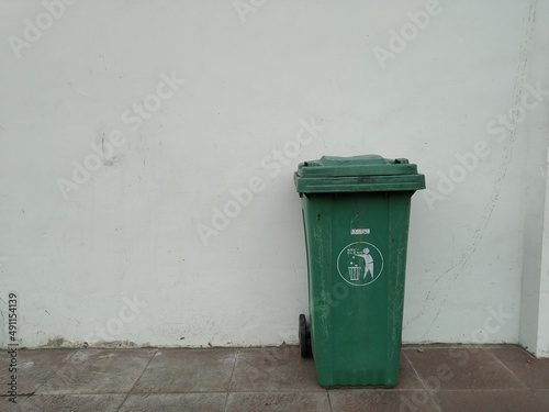 Green trash can white wall background