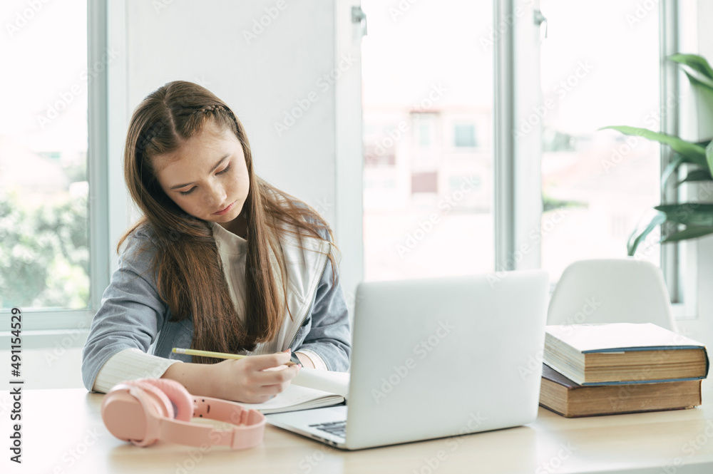 Girl student online learning class with laptop computer and book at home	