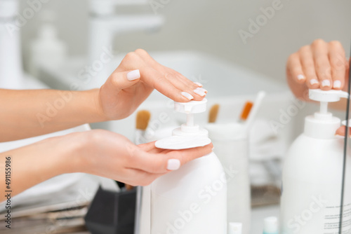 Beautiful female fingers with manicure squeezes a cosmetic onto a cotton pad. Concept of skin care and beauty routine