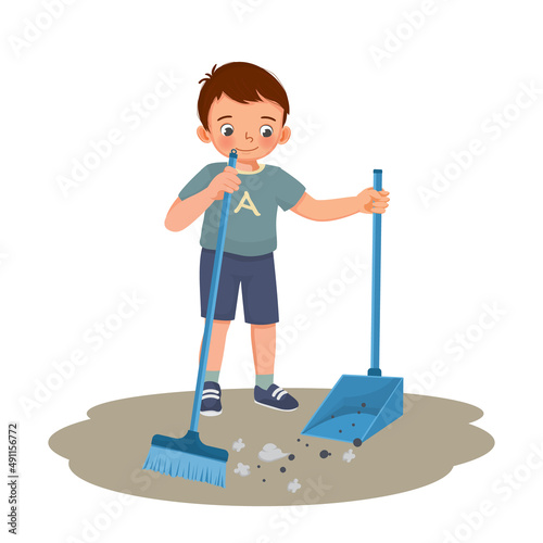cute little boy sweeping the floor with broom and scoop at living room doing daily routine housework chores