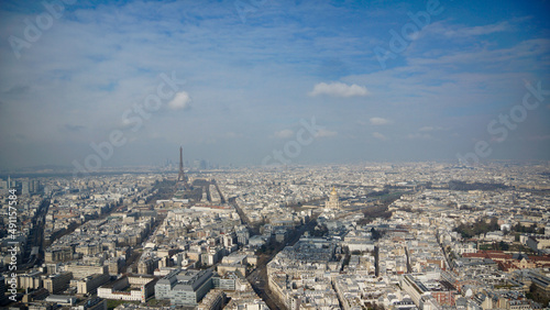 Ausblick vom Tour de Montparnasse auf den Eiffelturm und den Invalidendom sowie die Dächer von Paris von oben mit kleinen Wolken