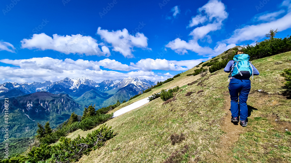 Woman hiking to the Frauenkogel (Dovska Baba) with scenic view on the Karawanks, Carinthia, Austria. Borders Austria, Slovenia, Italy. Triglav National Park. Mount Triglav and Mangart in the back. Awe