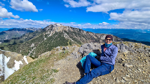 Hiker woman at the summit of Frauenkogel (Dovska Baba) with scenic view on mountain peaks in the Karawanks and Julian Alps, Carinthia, Austria. Border with Slovenia. Triglav National Park. Goal.Spring