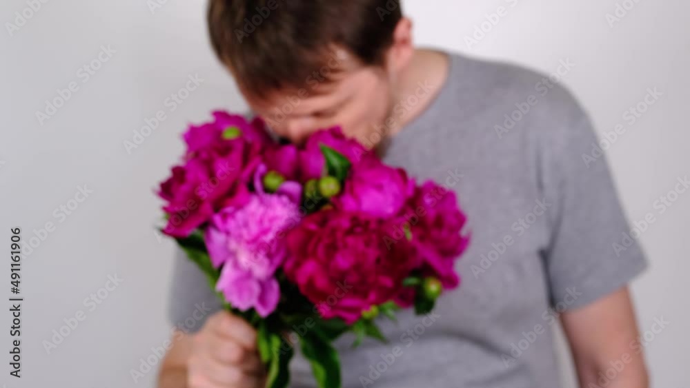 Man inhales fragrance of purple peonies and gives bouquet. Selective focus. Slow motion Man inhales fragrance of purple peonies and gives bouquet. Selective focus. Slow motion