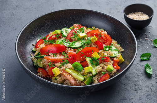 Salad with quinoa, tomatoes, cucumber, avocado and red pepper on a gray-blue background.