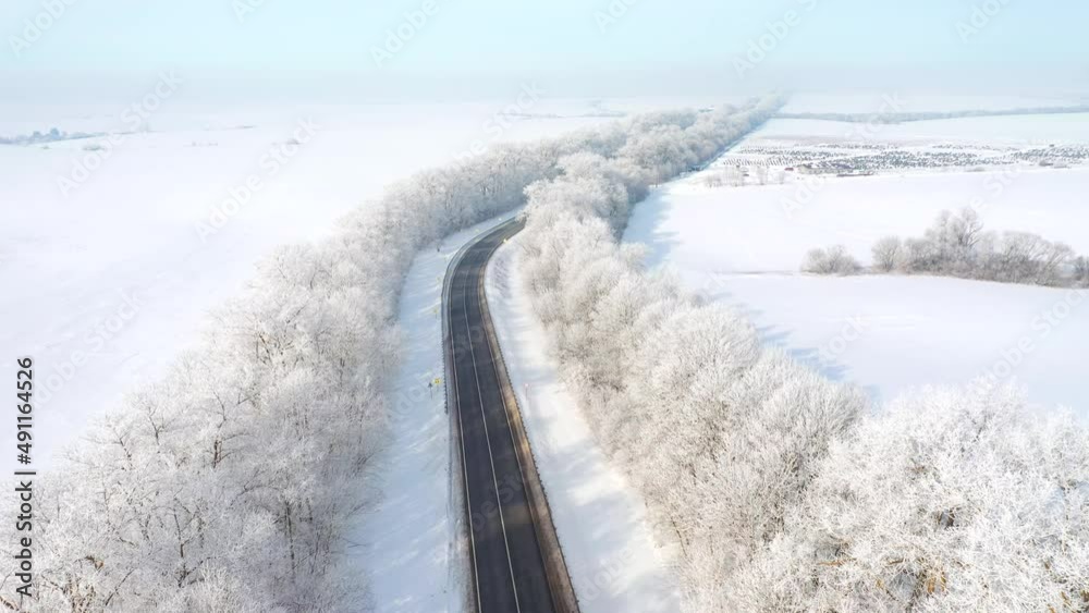 The drone flies over the highway that passes through snowy fields on a sunny day. Filmed in 4k video. The drone flies over the highway that passes through snowy fields on a sunny day. Filmed in 4k video.