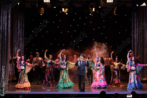 A group of musicians, singers and dancers in gypsy costumes perform on stage.