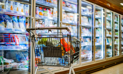 A shopping cart with grocery products in a supermarket