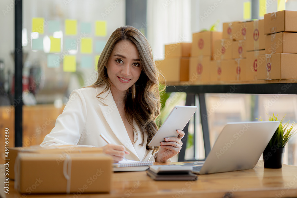 Woman owner of a startup company selling products online on an online store platform, sending goods through a courier company, Business planning. Online selling and online shopping concepts. Woman owner of a startup company selling products online on an online store platform, sending goods through a courier company, Business planning. Online selling and online shopping concepts.