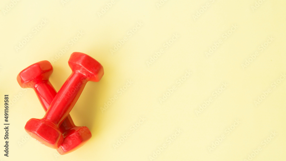 Two red dumbbells on a yellow background Two red dumbbells on a yellow background