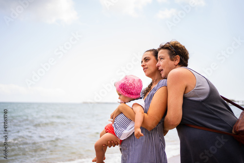 Family of three generation of women embracing next to the beach