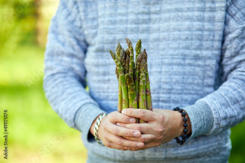 Man holding a bunch of green asparagus in his hands outdoor