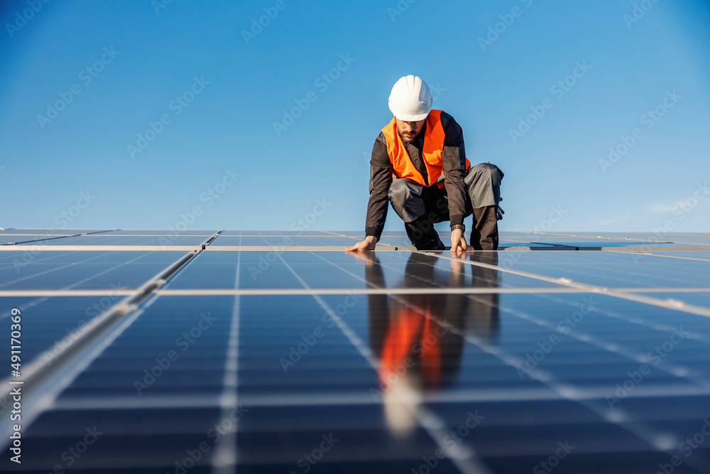 A handyman installing solar panels on the rooftop. - obrazy, fototapety, plakaty 