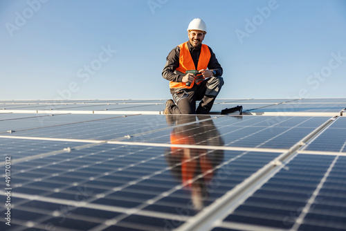 A handyman holding electrical screwdriver and preparing to install solar panels on the roof. photo
