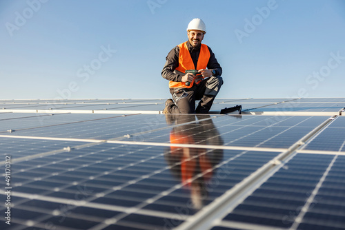 Bild auf Leinwand A handyman holding electrical screwdriver and preparing to install solar panels on the roof