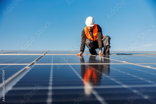 A handyman installing solar panels on the rooftop. photo