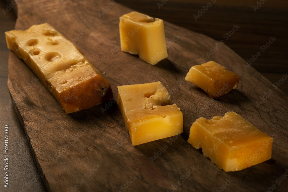 Sliced Kars Gruyere cheese on a wooden cutting board Sliced Kars Gruyere cheese on a wooden cutting board