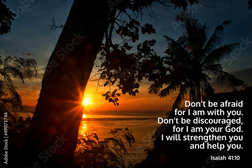 Bible verse inspiraitonal quote - Don't be afraid for I am with you. Don't be discouraged for I am your God. I will strengthen you and help you. Isaiah 41:10. On tropical sunset sunrise background. photo