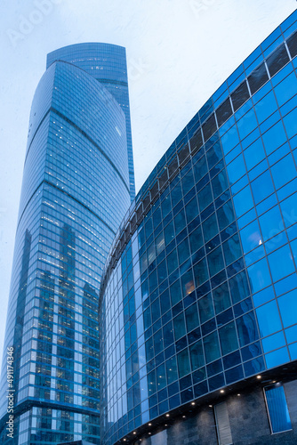 The tops of modern corporate buildings in snowfall. Low angle view of skyscrapers.