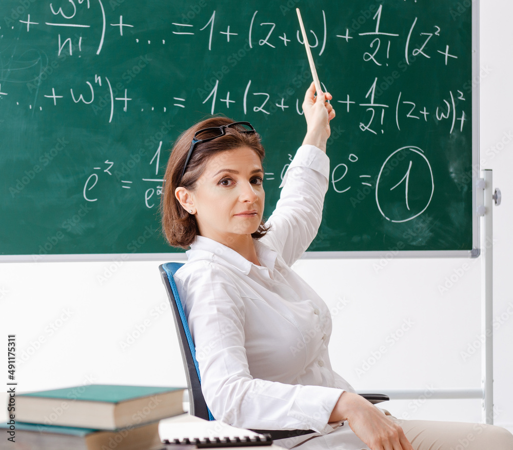The female math teacher in front of the chalkboard The female math teacher in front of the chalkboard