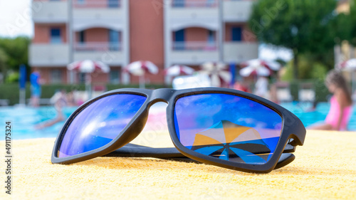 Sunglasses closeup summer background. Beach pool equipment with travel sunglasses on yellow holiday towel. Outdoor relax holiday at ocean.