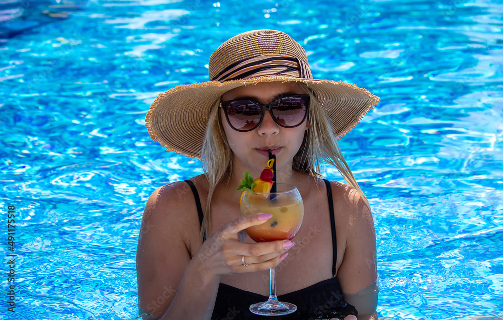 girl drinks a cocktail in the pool.