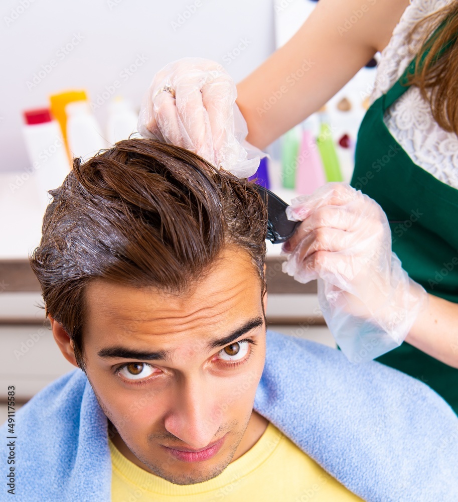 Fototapeta premium The woman hairdresser applying dye to man hair