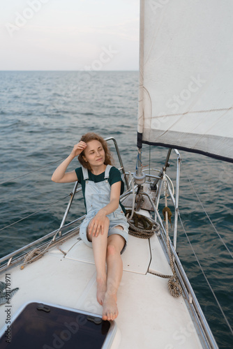 A redhead woman is sitting on a yacht and enjoying a trip by the sea © Ivan Kozachenko