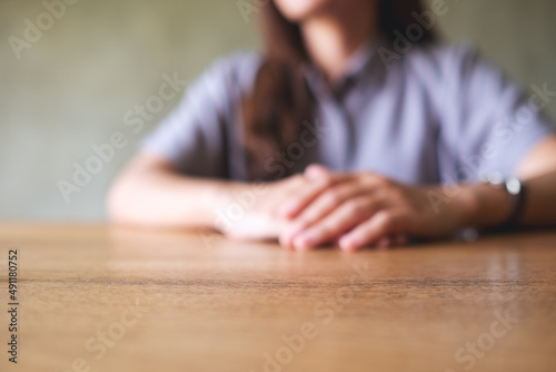 Closeup blurred image of a woman with holding hands while thinking, waiting, praying or making decision