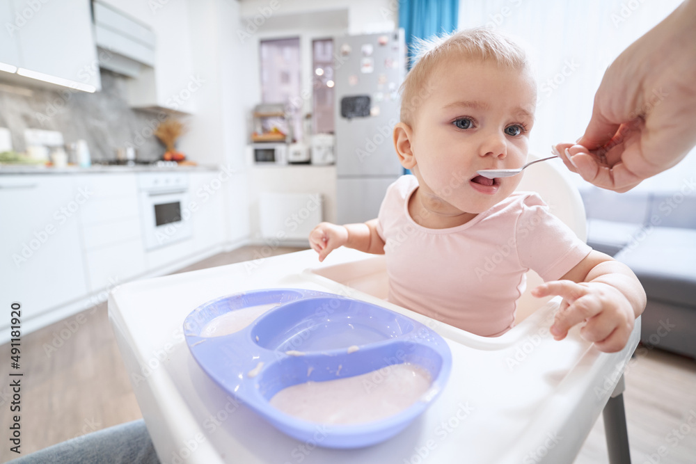Charming tiny girl in pink clothes at the morning breakfast at home Charming tiny girl in pink clothes at the morning breakfast at home