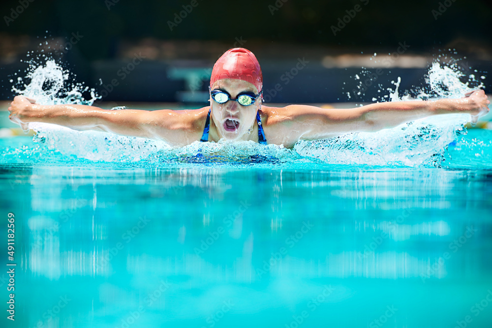 The hardest stroke in swimming.... Shot of a young female swimmer doing the butterfly stroke.