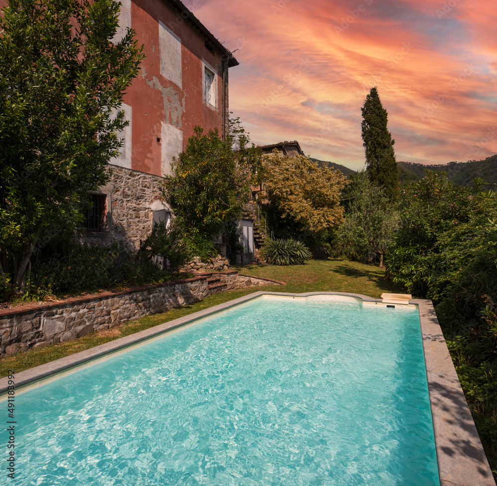 Exterior of Italian villa in Tuscany with swimming pool. Sunset view, romantic scenery.