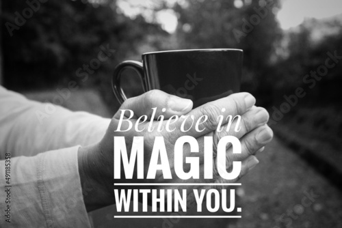 Inspirational quote - Believe in magic within you. With hands of a person holding cup of coffee in monochrome black and white abstract art background. Self confidence. Believe in yourself concept. photo