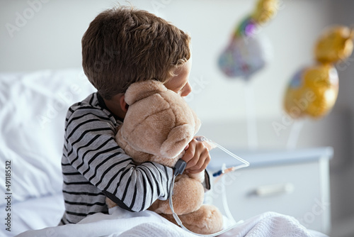 Child hugging teddy bear at hospital photo