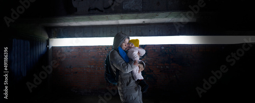 Photographie Exhausted mother holding her child in arms in the bomb shelter
