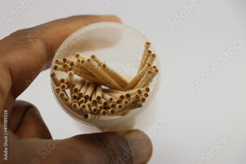 Toothpicks in its container held in hand on a white background