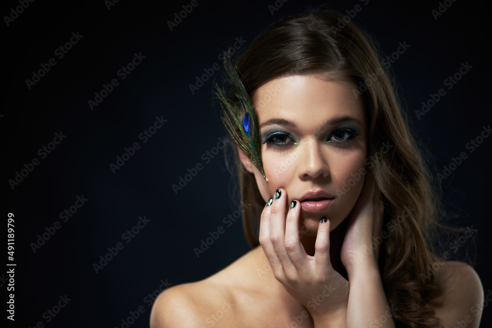 Capturing a dramatic beauty. Shot of a young brunette with peacock-themed makeup against a dark background. Capturing a dramatic beauty. Shot of a young brunette with peacock-themed makeup against a dark background.